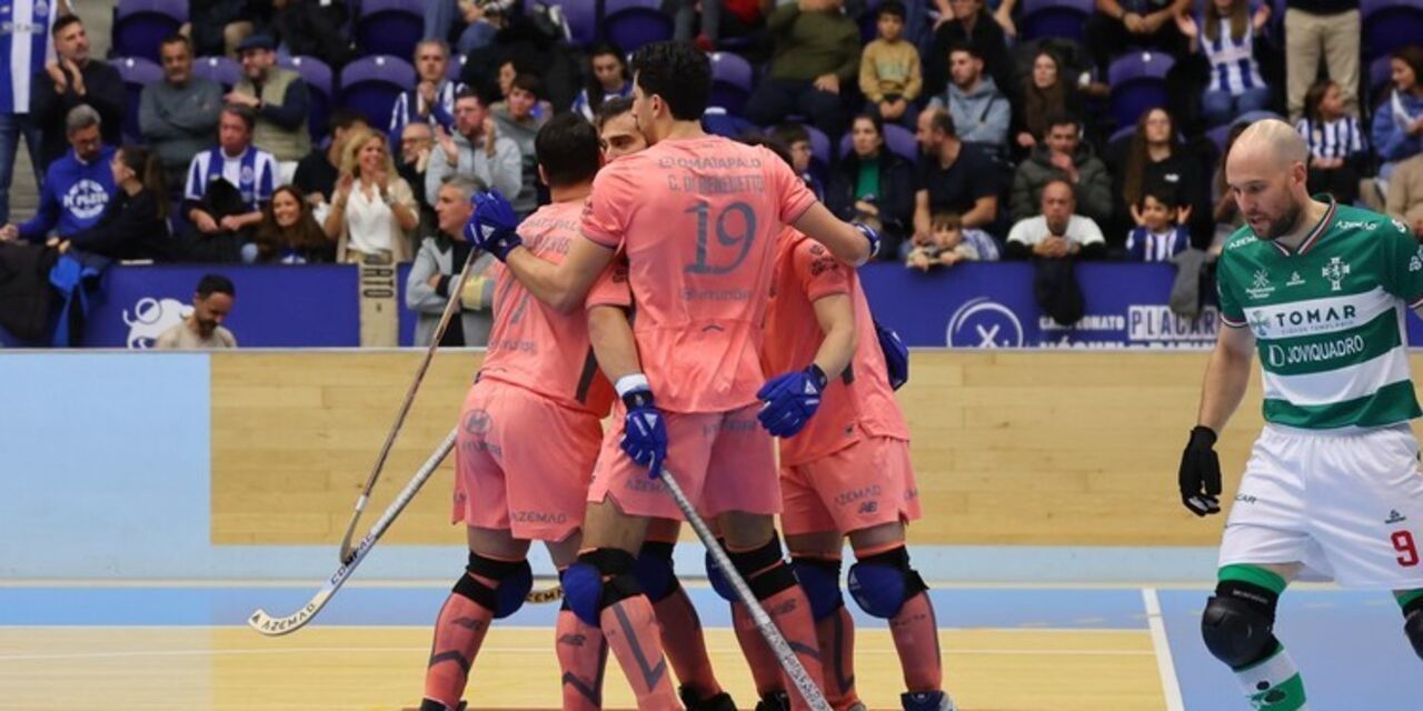 Jogadores de hóquei celebram em campo, com o público nas bancadas
