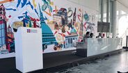 Evento da Regione Piemonte com painelistas em frente a um mural colorido