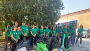 Grupo de pessoas participa numa ação de limpeza ao ar livre com sacos cheios de lixo