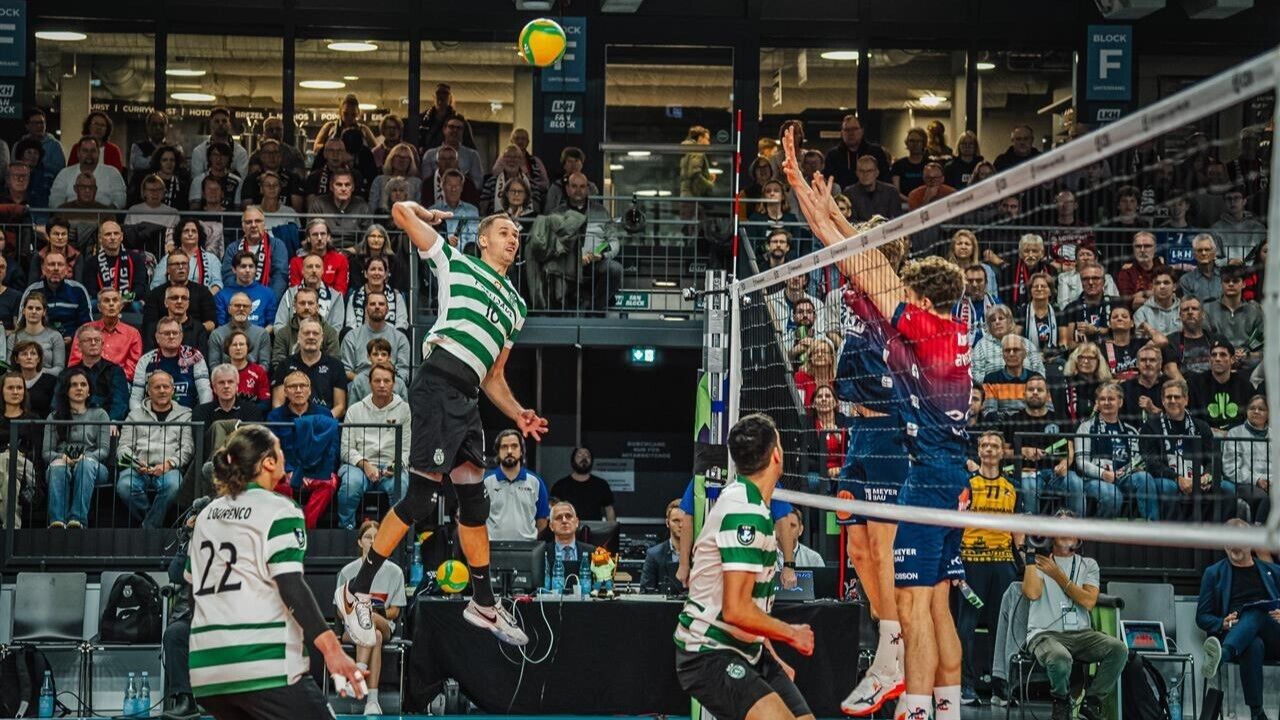 Partida de voleibol com jogadores em ação e público atento