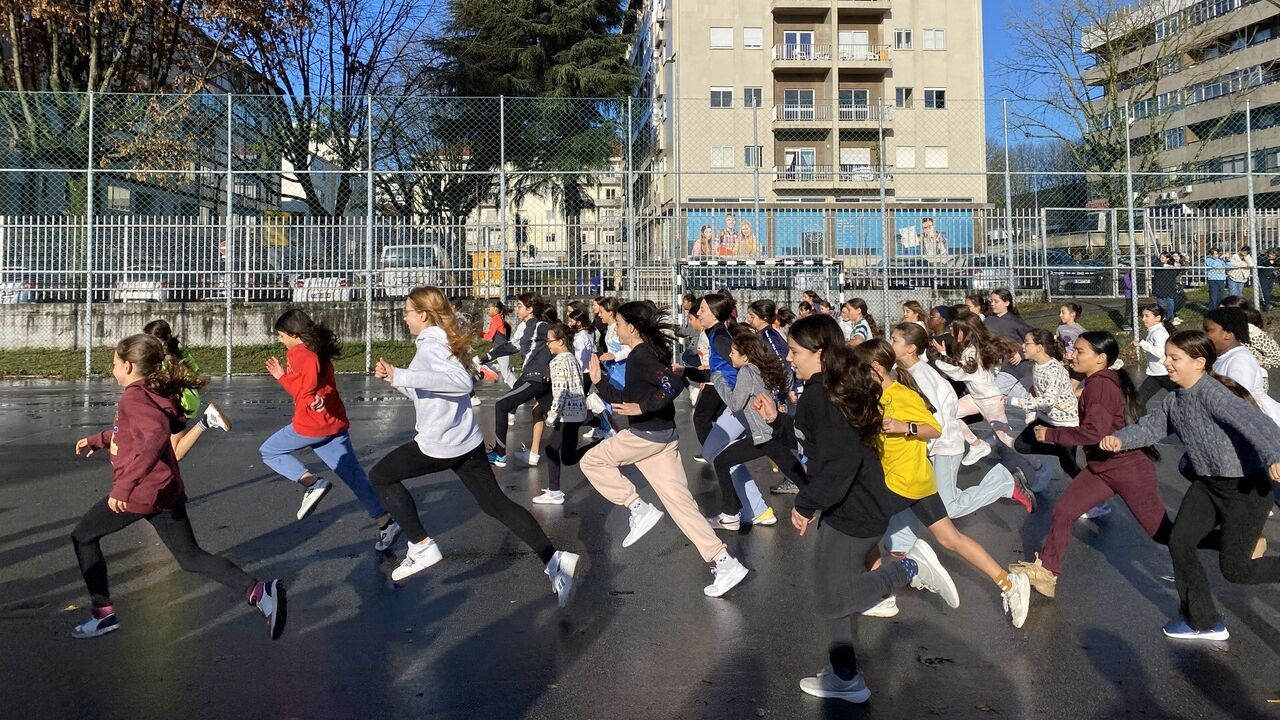Grupo de raparigas corre num recinto escolar ao ar livre