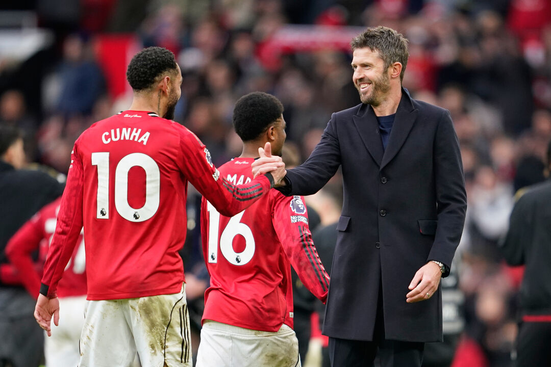 Michael Carrick sorridente a cumprimentar os jogadores após vitória no dérbi de Manchester