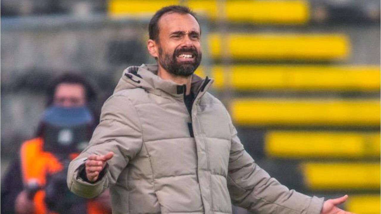 Treinador gesticula no relvado durante jogo de futebol