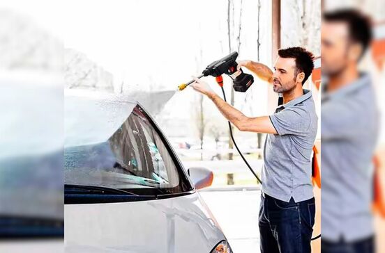 Homem lava carro com máquina de pressão. Acessório prático para limpeza