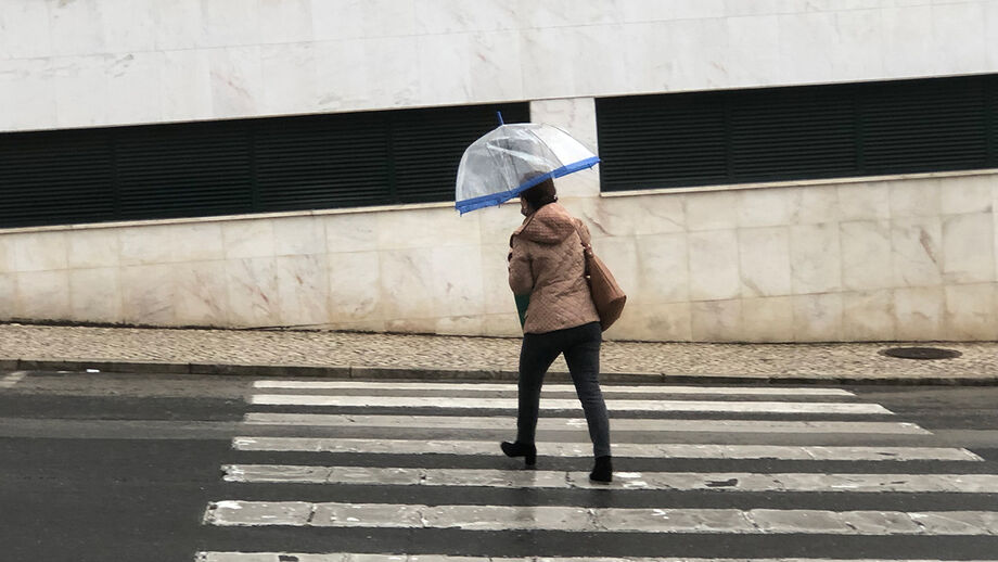 Mulher atravessa passadeira com guarda-chuva
