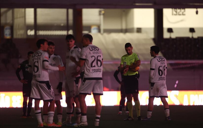 Árbitro e jogadores em campo durante jogo noturno em Guimarães