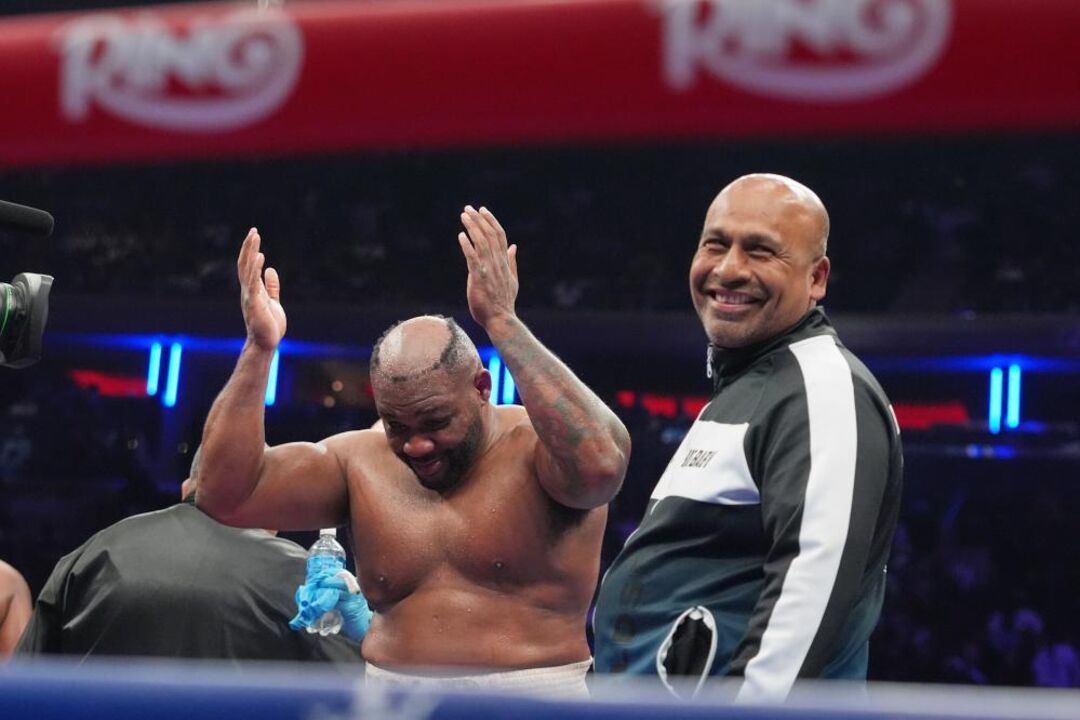 Pugilista comemora vitória no ringue sob o olhar atento do treinador