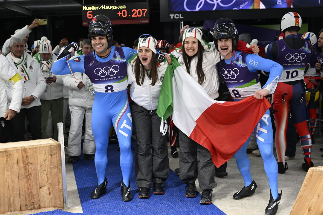 Atletas italianos celebram com a bandeira de Itália