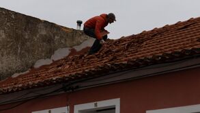 Homem repara telhado danificado pela tempestade Kristin em Portugal