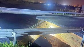 Estrada danificada após colapso, com parte do asfalto em falta