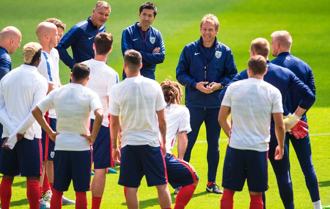 Jogadores de futebol e treinadores reunidos no campo
