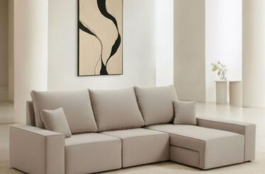 Sala decorada com sofá bege, quadro abstrato e flores