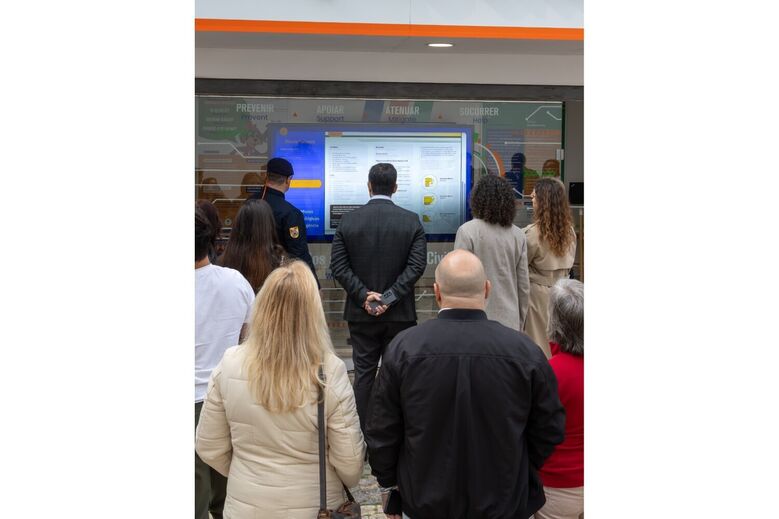 Pessoas consultam informações de prevenção e apoio em ecrã interativo