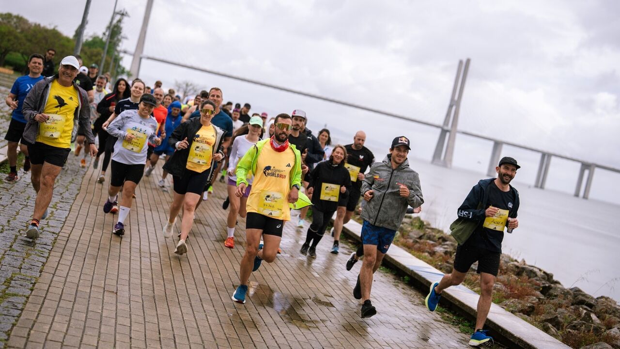 Corredores participam numa corrida junto ao rio Tejo, com a Ponte Vasco da Gama como pano de fundo