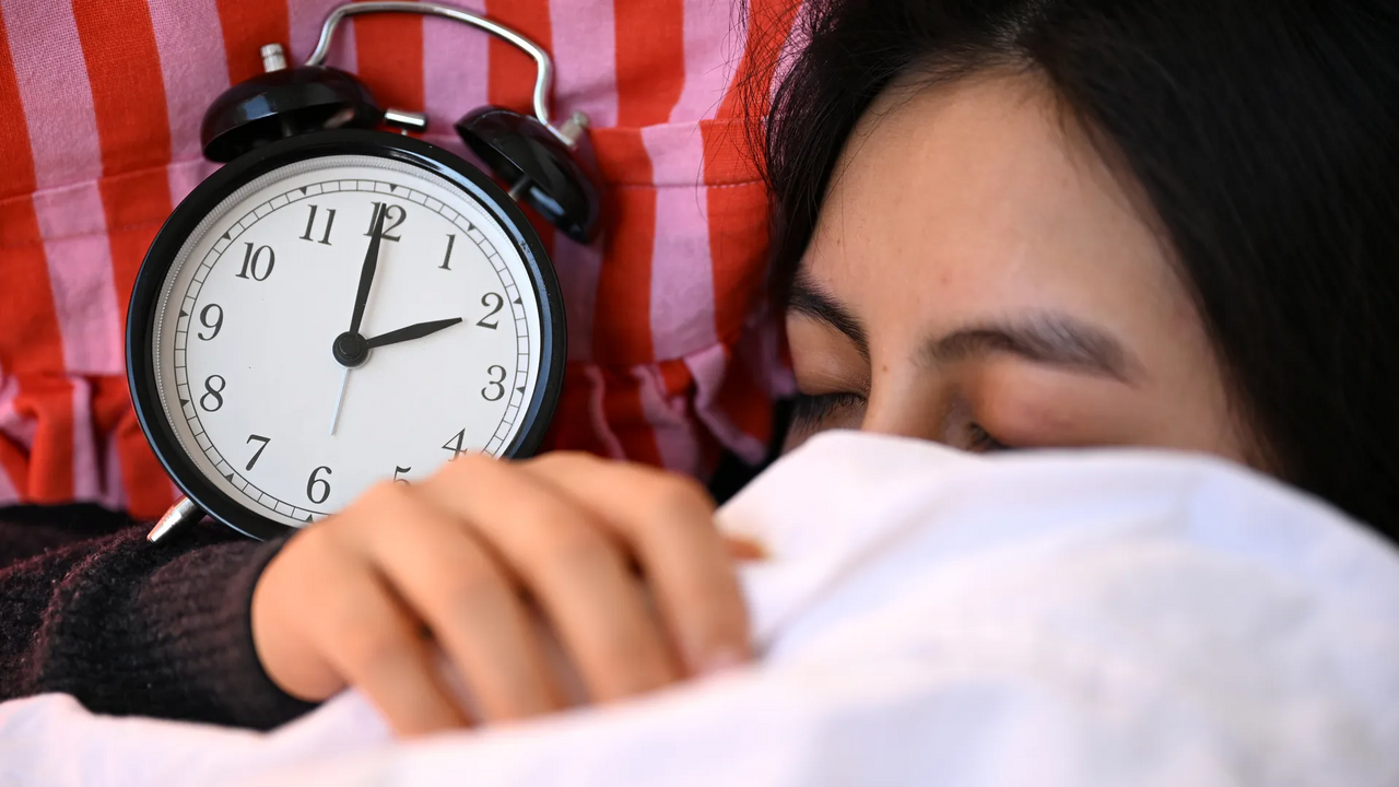 Mulher ao lado de despertador, para dormir bem e seguir tendência do sleepmaxing