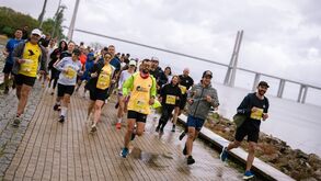 Corredores participam numa corrida junto ao rio Tejo, com a Ponte Vasco da Gama como pano de fundo