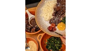 Prato de feijoada com arroz, laranja, couve e farofa