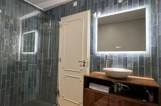 Casa de banho Mudelar: espaço moderno com azulejos cinzentos, espelho iluminado e lavatório elegante