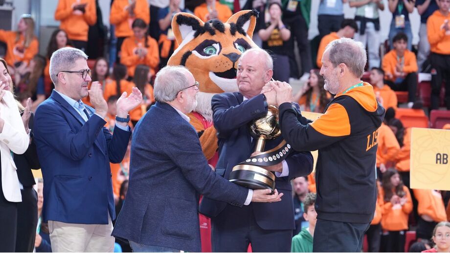 Cerimónia de entrega de troféu com pessoas, uma mascote e público