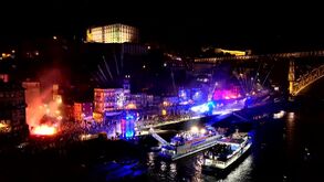 Espetáculo de luzes noturno no Porto, com multidão e fogo de artifício junto ao rio Douro