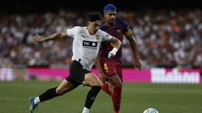 Futebolistas do Valência e do Barcelona disputam a bola em jogo
