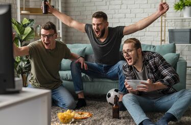 Amigos reunidos vibram em frente à TV durante um jogo do Mundial 2026
