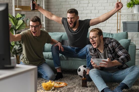 Amigos reunidos vibram em frente à TV durante um jogo do Mundial 2026