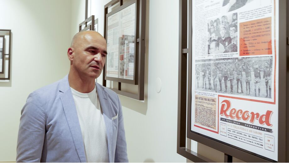 Homem observa capas do jornal Record numa exposição