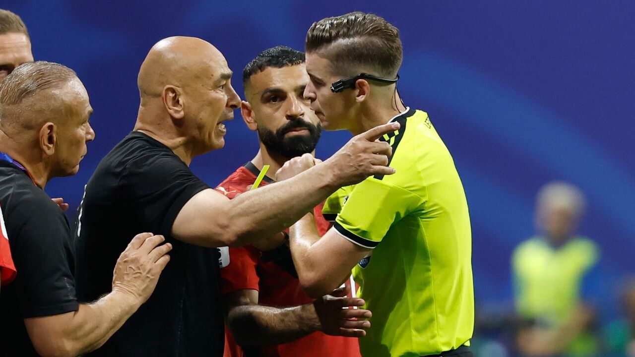 Hossam Hassan, selecionador do Egito, contesta o árbitro François Letexier durante o Argentina-Egito