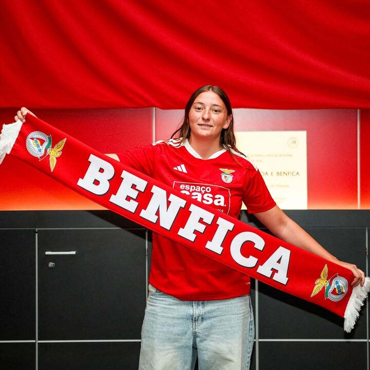Jogadora segura cachecol do Benfica em frente a fundo vermelho