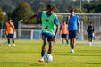 Jogador de futebol treina com bola num campo de relva