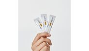 Mão segura 3 ampolas de Heliocare 360º Junior Oral Sticks