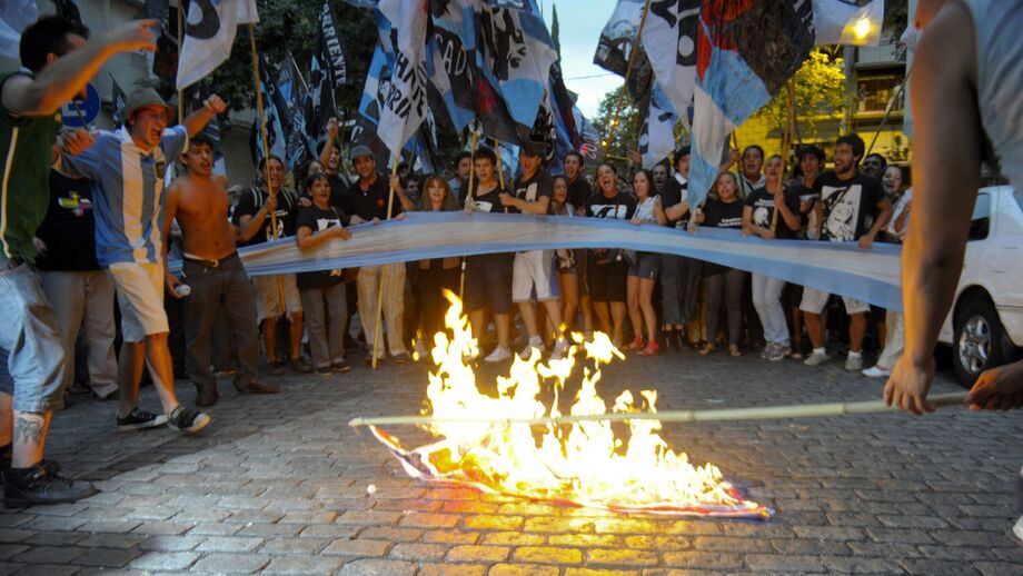 Manifestantes queimam uma bandeira britânica em protesto contra a chegada do Príncipe William às Ilhas Malvinas, no exterior da Embaixada do Reino Unido em Buenos Aires, na Argentina, em 2012