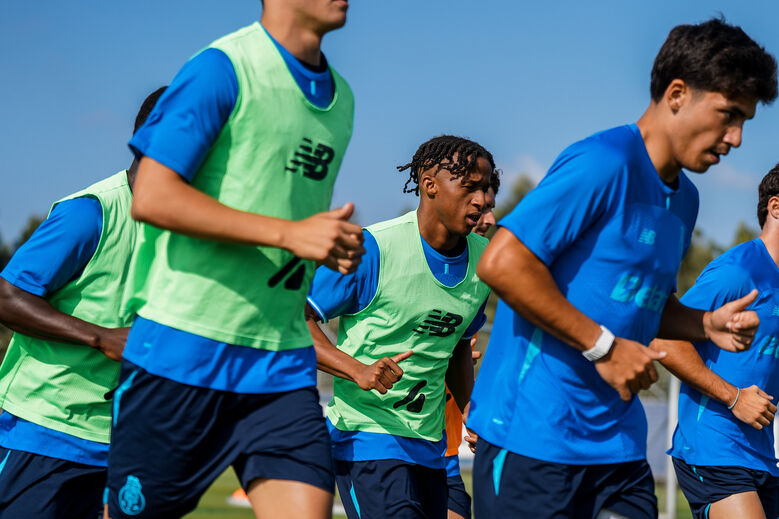Jogadores de futebol em treinamento com coletes verdes e camisetas azuis