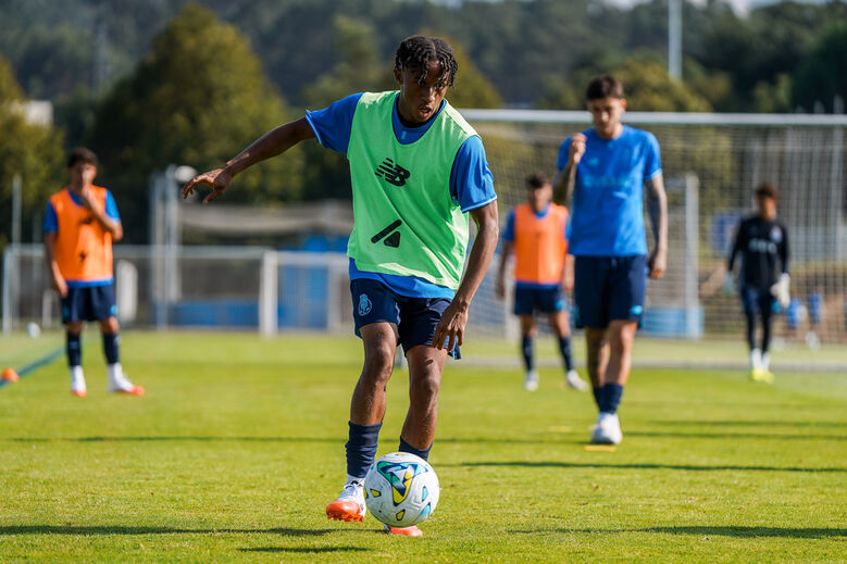 Jogador de futebol treina com bola num campo de relva