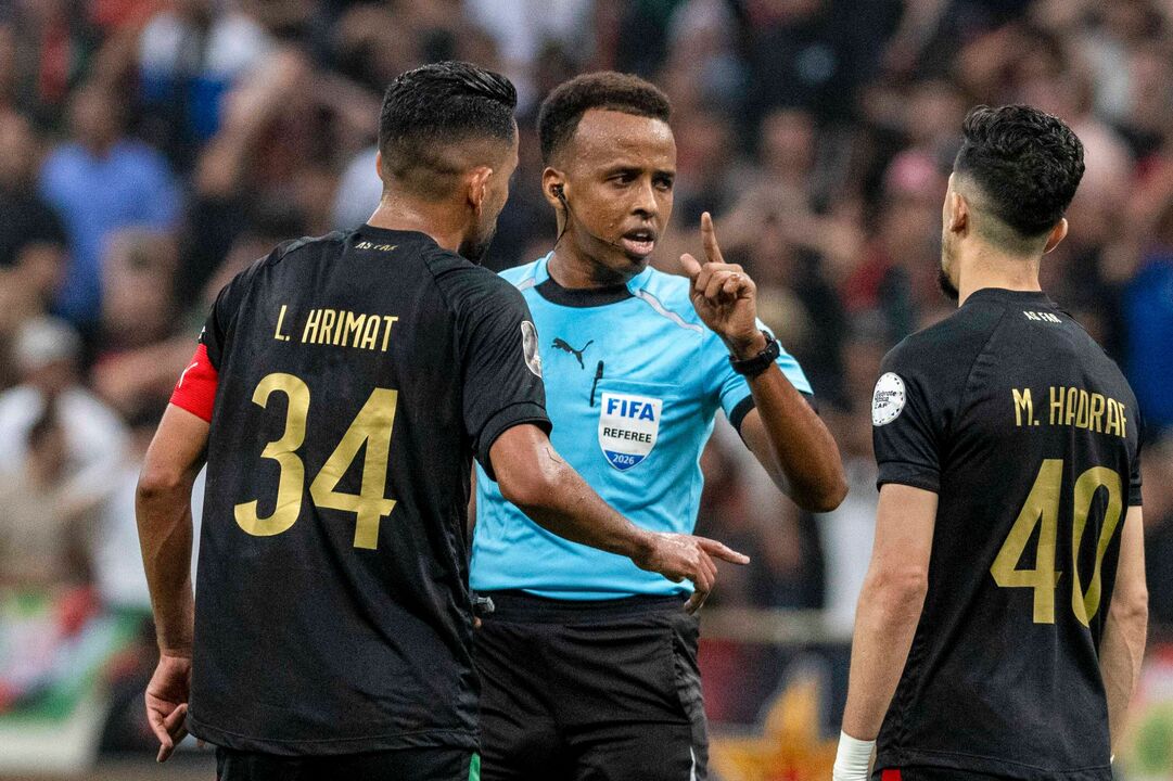 FILE - Referee Omar Artan, center, of Somalia, is confronted by players after calling a penalty kick during the CAF