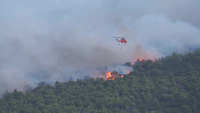 Helicóptero combate incêndio florestal em região da Grécia
