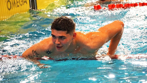 Nadador emerge da piscina com tattoo no braço