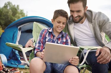 Pai e filho no campismo usam um tablet