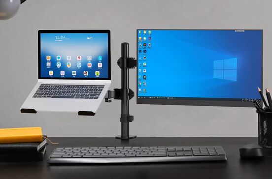 Um portátil e um monitor de computador estão numa secretária com um teclado