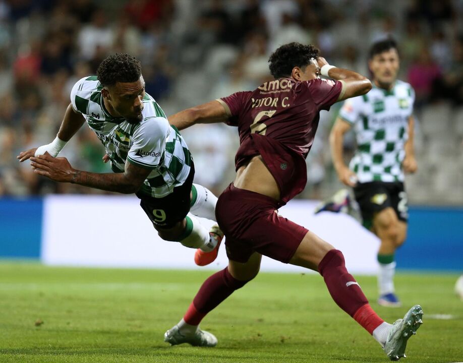 Os jogadores disputam a posse da bola no relvado no