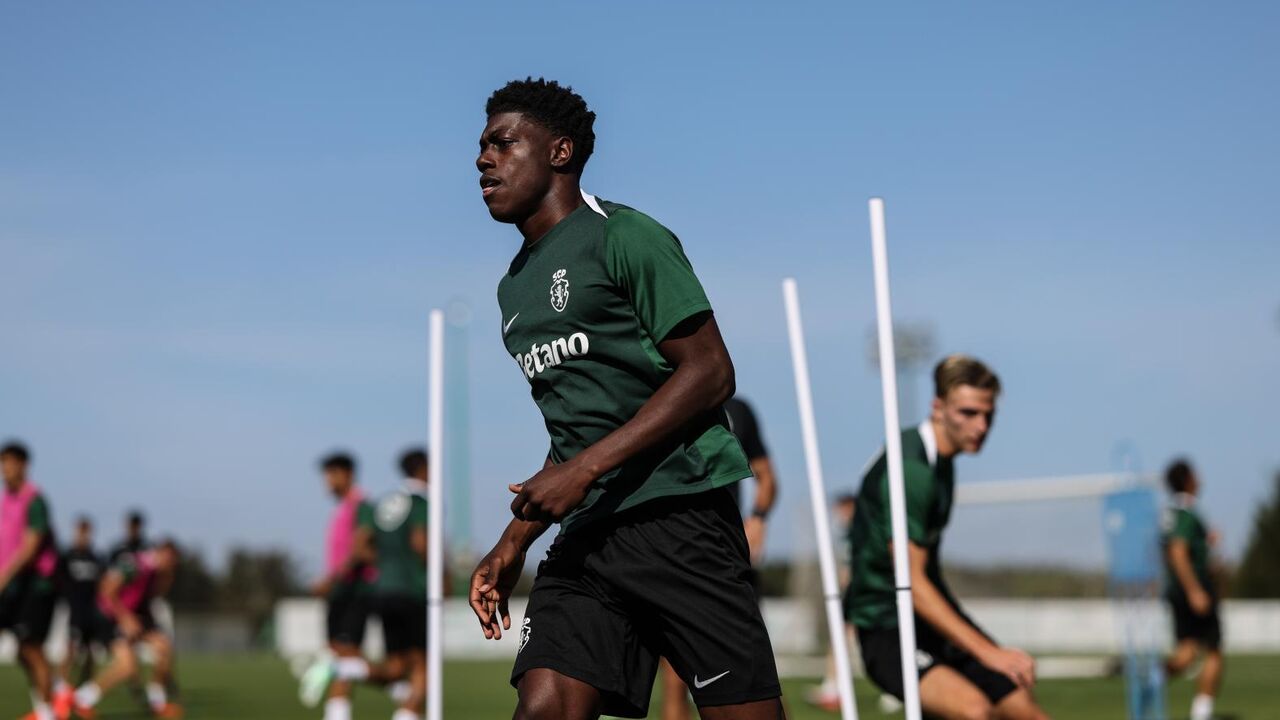 Jogador de futebol corre durante treino em campo com outros atletas