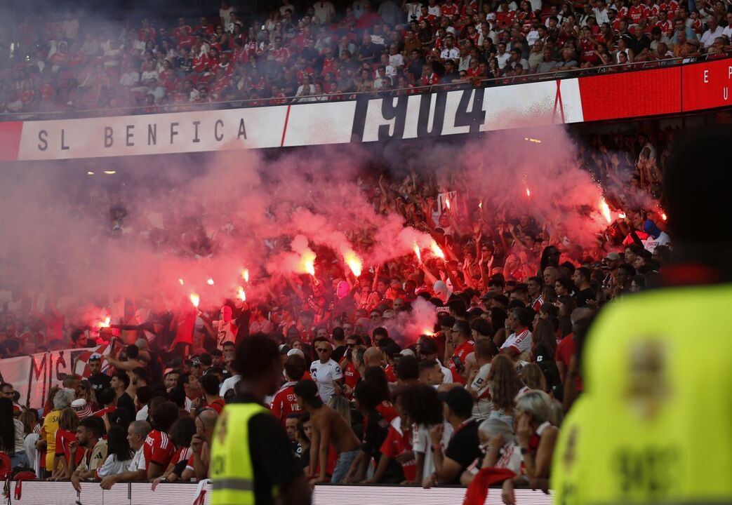 Adeptos com tochas na bancada, durante o jogo