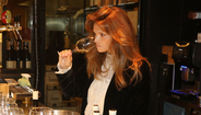Mulher com cabelo ruivo avalia um copo de vinho branco