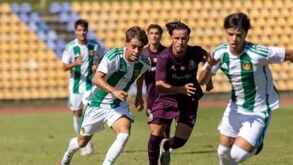 Jogadores de futebol correm no campo de relva com a bancada ao fundo