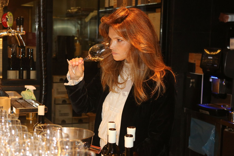 Mulher com cabelo ruivo avalia um copo de vinho branco