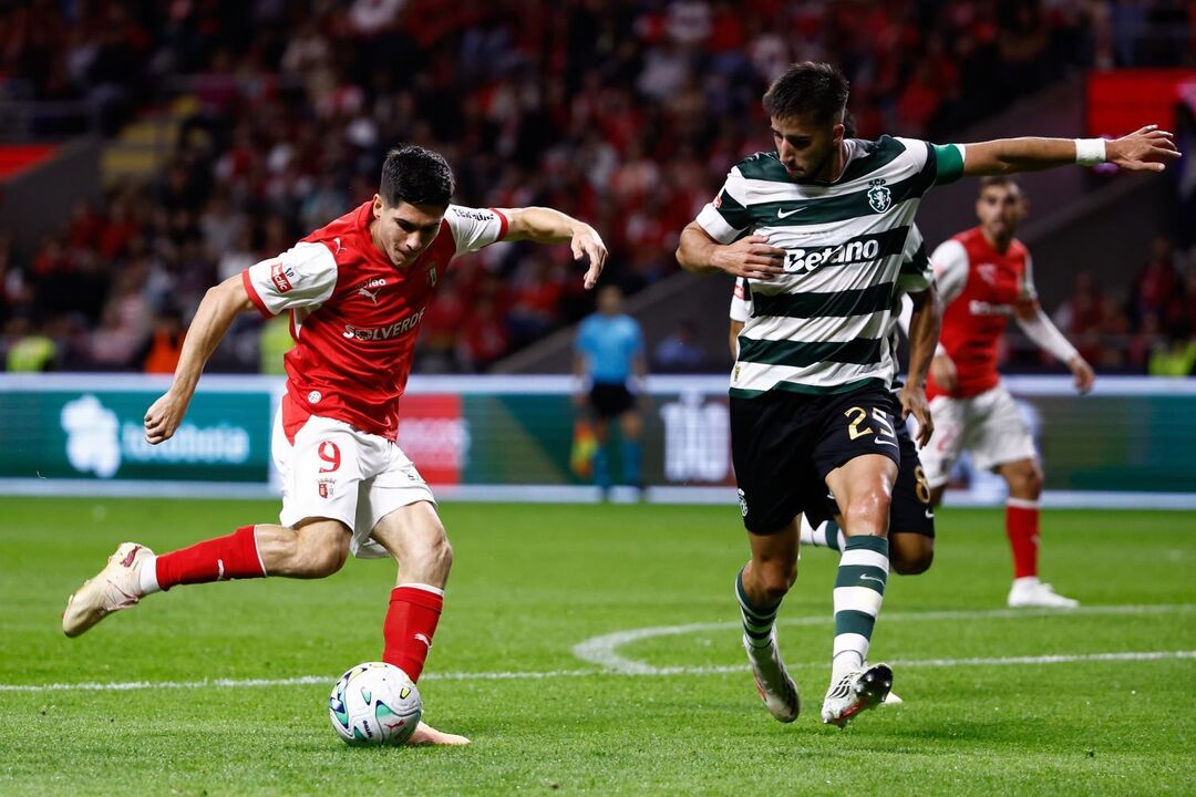 Os jogadores disputam a posse da bola no relvado no