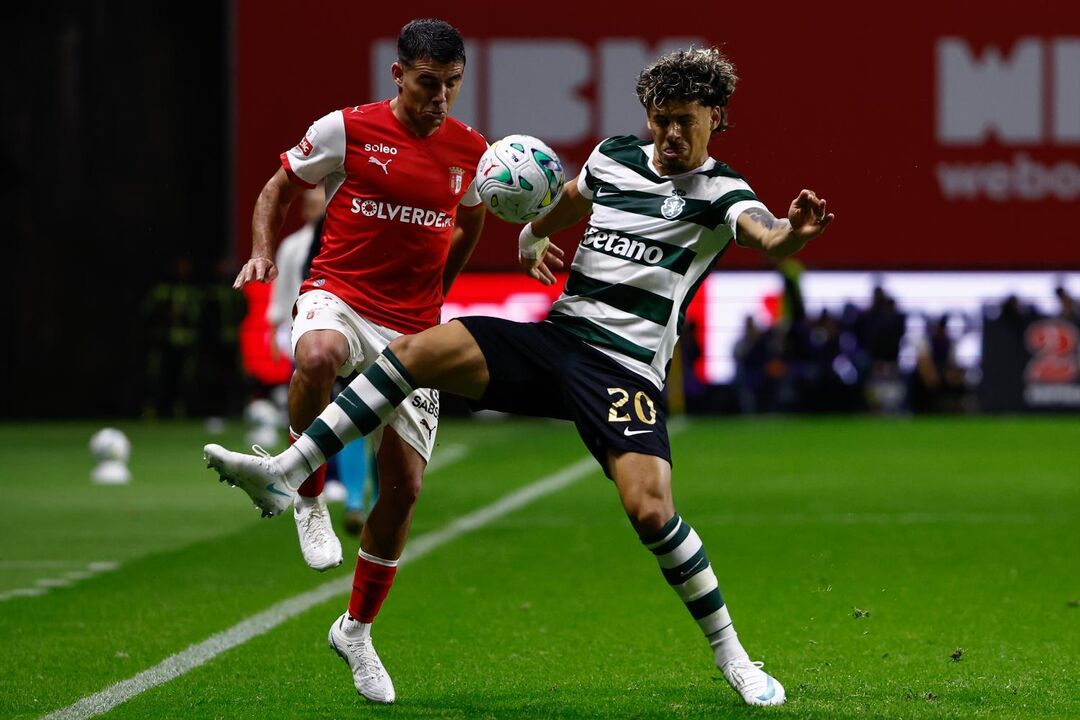 Os jogadores disputam a posse da bola no relvado no