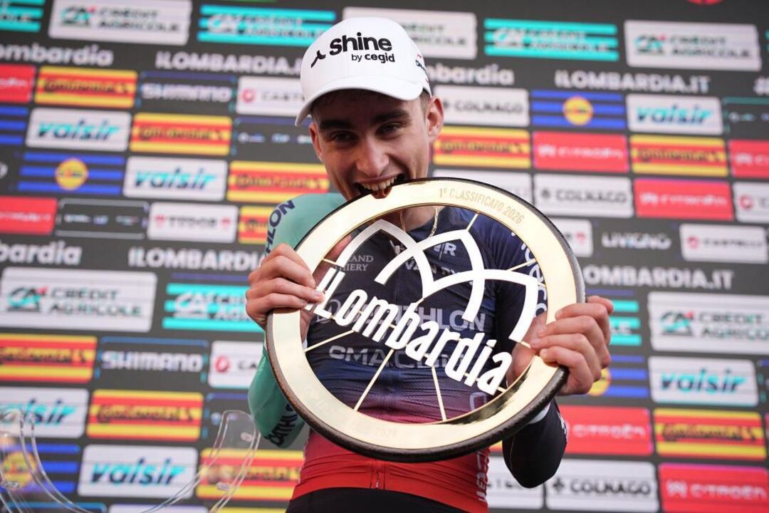 France's Paul Seixas bites thew trophy after winning Il Lombardia,
