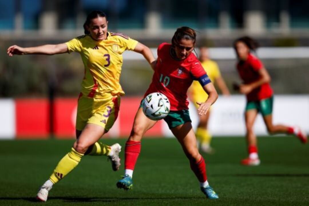 Jogadoras de futebol disputam a bola em campo